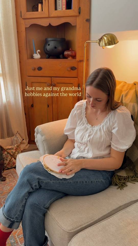 Nicole stitching an embroidery hoop on her sofa